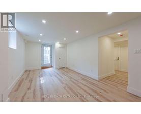 A spacious room with wooden flooring and white walls.