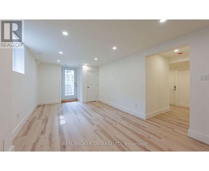 A spacious room with wooden flooring and white walls.