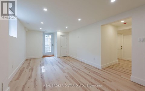A spacious room with wooden flooring and white walls.