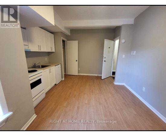 A kitchen with white cabinets and a wooden floor.