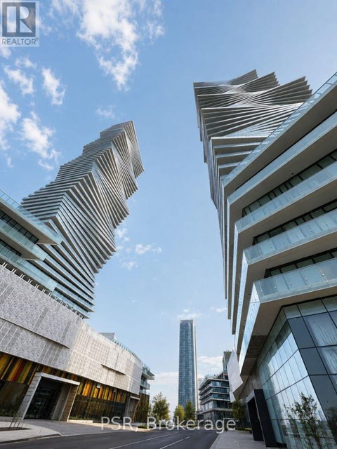 A modern building with a curved facade stands tall against a blue sky.