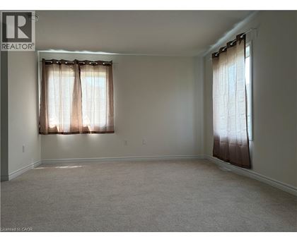 A room with a carpeted floor and two windows with curtains.