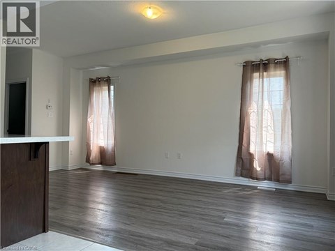 A room with a wooden floor and a window with curtains.