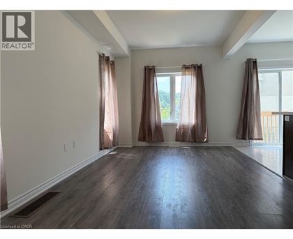 A room with wooden floors and two windows with curtains.