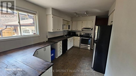 A kitchen with black and white appliances and cabinets.