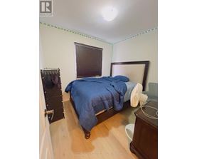 A bedroom with a bed, nightstand, and window with blinds.
