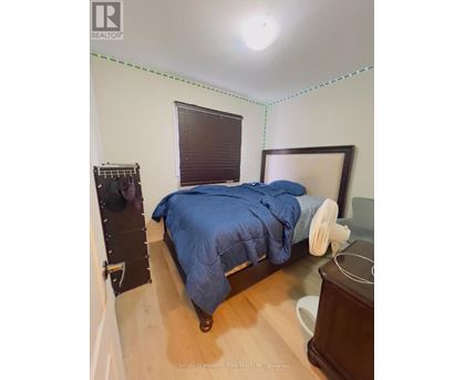 A bedroom with a bed, nightstand, and window with blinds.