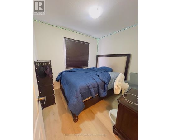 A bedroom with a bed, nightstand, and window with blinds.