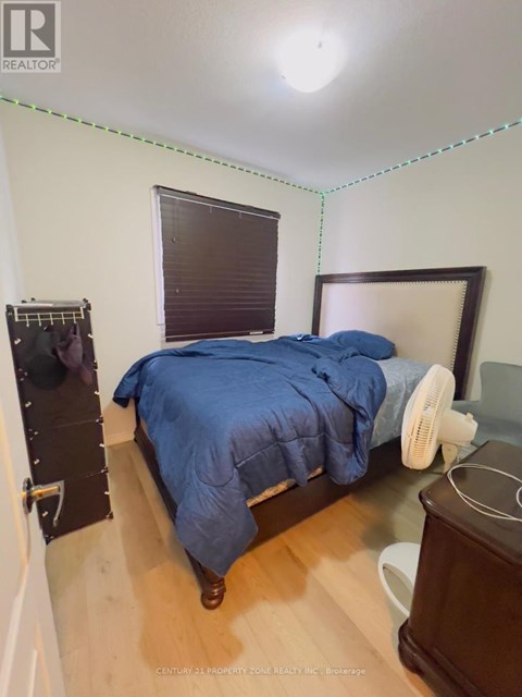 A bedroom with a bed, nightstand, and window with blinds.