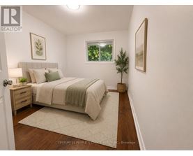 A bedroom with a bed, nightstand, and a plant.