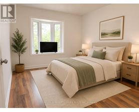 A bedroom with a large bed, a small tree, and a painting on the wall.