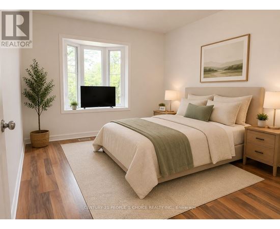 A bedroom with a large bed, a small tree, and a painting on the wall.