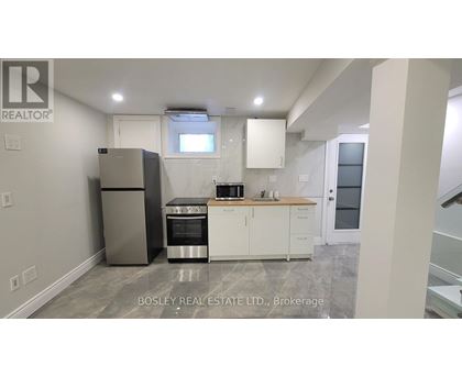 A kitchen with a refrigerator, oven, and cabinets.