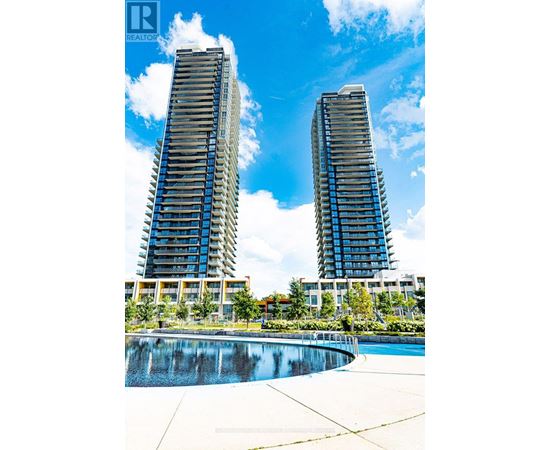Two tall buildings with balconies are reflected in a pool.