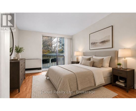 A bedroom with a large bed, a nightstand, and a window overlooking a balcony.