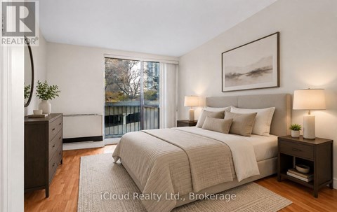 A bedroom with a large bed, a nightstand, and a window overlooking a balcony.