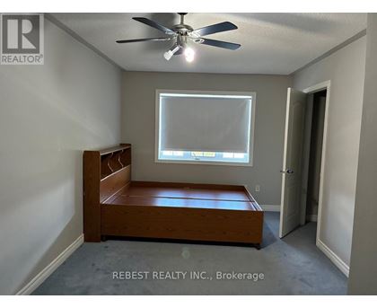 A bedroom with a bed, a window, and a ceiling fan.