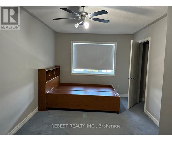 A bedroom with a bed, a window, and a ceiling fan.