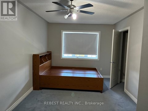 A bedroom with a bed, a window, and a ceiling fan.