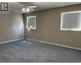 A room with a ceiling fan and two windows.