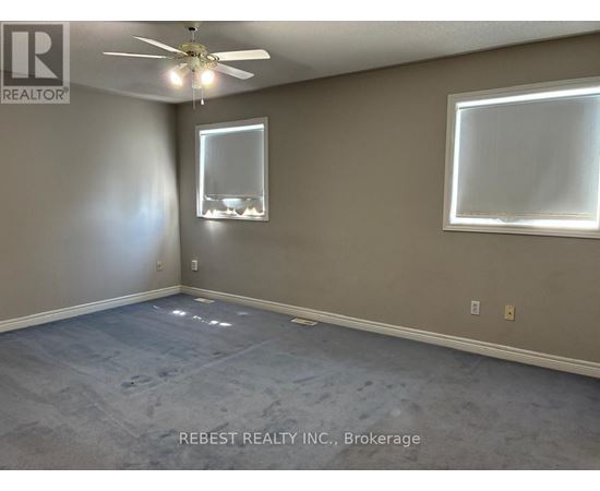 A room with a ceiling fan and two windows.