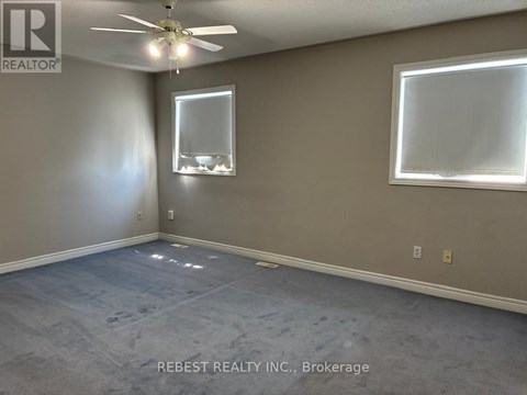 A room with a ceiling fan and two windows.