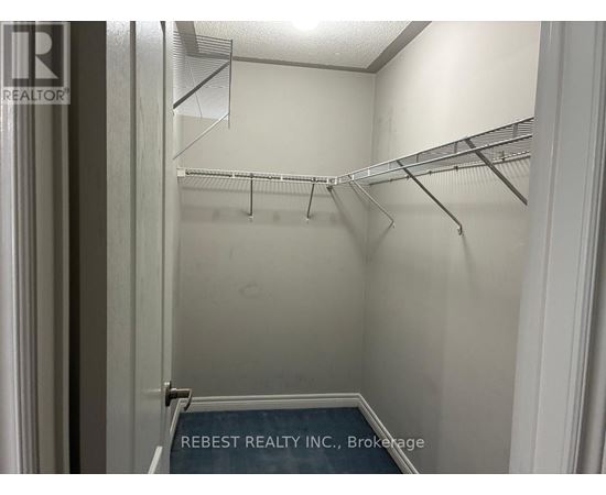 Empty walk in closet with shelves and a sign that says Rebest Realty Inc Brokerage.