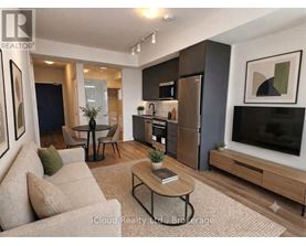 A modern living room with a beige sofa, a black coffee table, and a flat-screen TV.