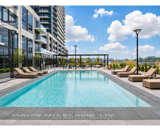 A large swimming pool with lounge chairs and a sign that says "Shallow Area, No Diving 1.3m" in front of a building.