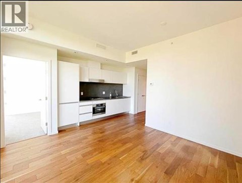 A spacious room with wooden flooring and a television.
