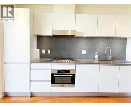 A modern kitchen with white cabinets and a stainless steel oven.
