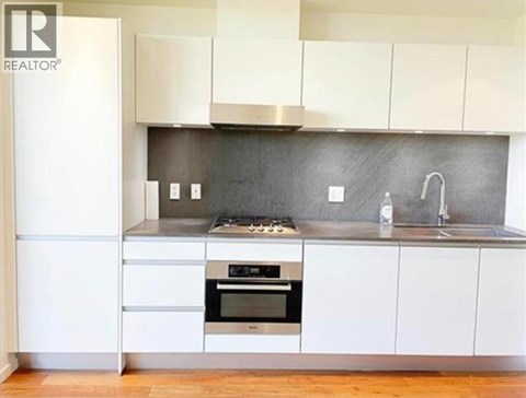 A modern kitchen with white cabinets and a stainless steel oven.