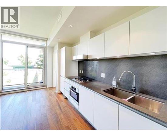 A modern kitchen with white cabinets and a wooden floor.