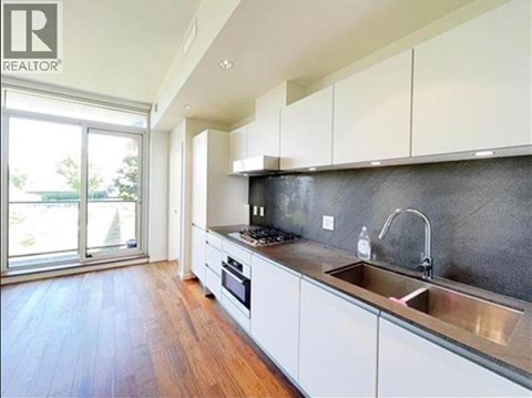 A modern kitchen with white cabinets and a wooden floor.