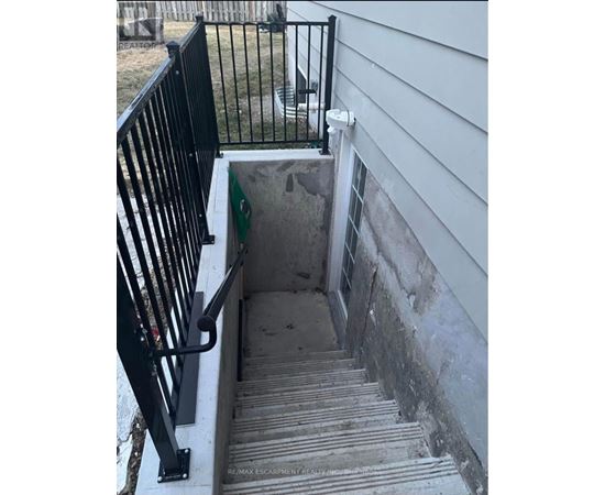 A stairway with a black railing leading to a concrete area.