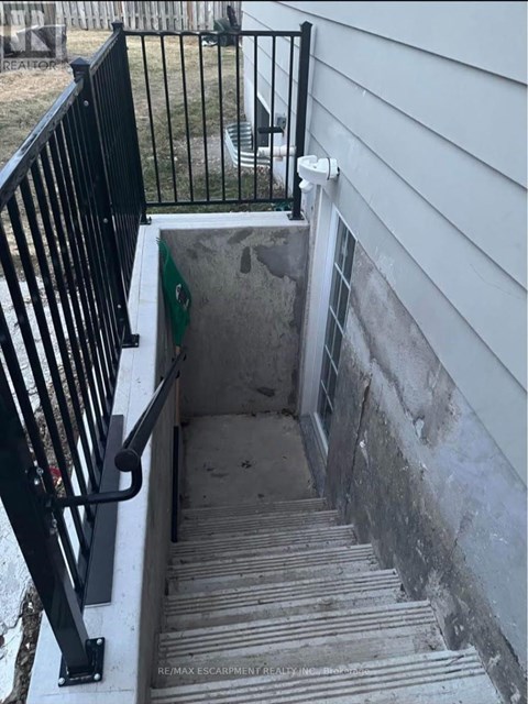 A stairway with a black railing leading to a concrete area.