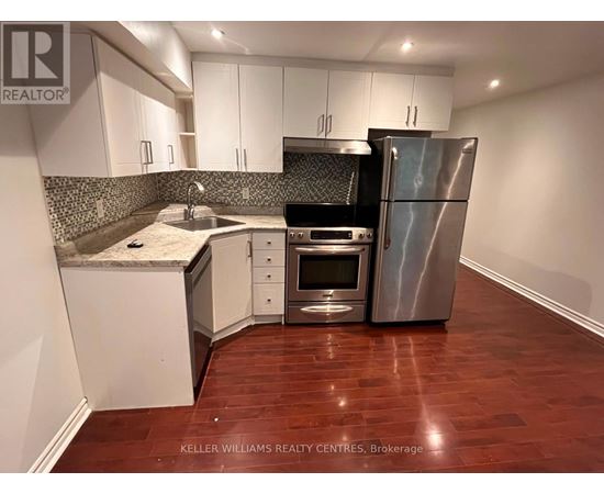 A kitchen with a refrigerator, oven, and sink.