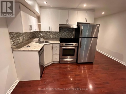 A kitchen with a refrigerator, oven, and sink.