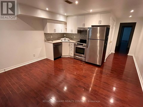 A kitchen with stainless steel appliances and wooden floors.