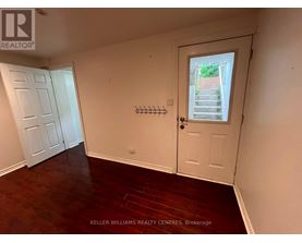 A room with a door and a window with a view of a garden outside.