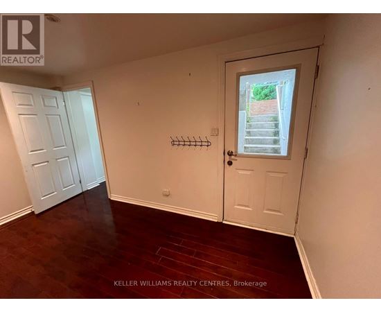A room with a door and a window with a view of a garden outside.