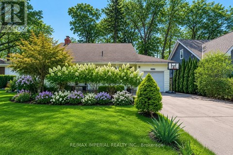 A well-maintained lawn with a variety of flowers and shrubs in front of a house.