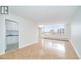A spacious room with wooden flooring and a view of the city through the window.