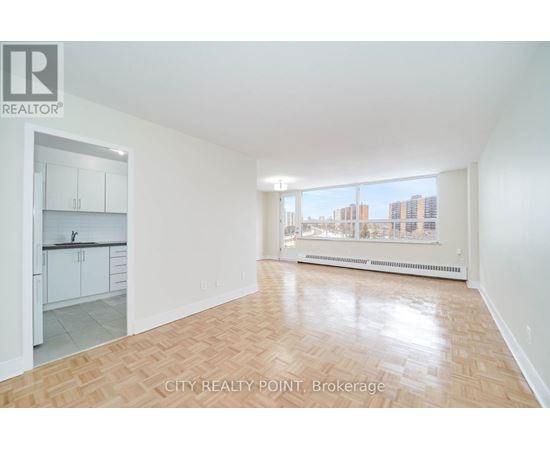 A spacious room with wooden flooring and a view of the city through the window.