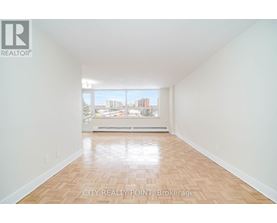 A large empty room with wooden floors and a view of the city through the window.