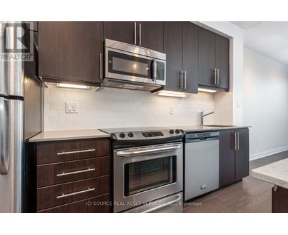 A modern kitchen with dark brown cabinets and stainless steel appliances.
