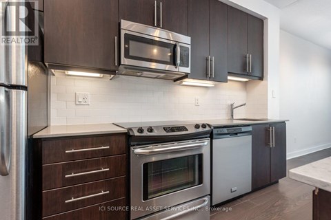 A modern kitchen with dark brown cabinets and stainless steel appliances.