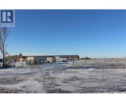 A snowy field with a building and a fence in the background.