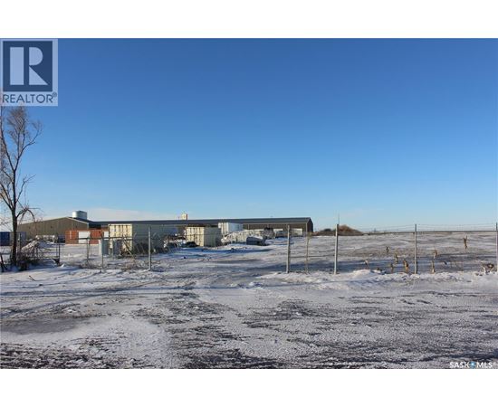 A snowy field with a building and a fence in the background.