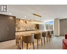 A modern dining room with a stone wall and a long table with chairs.